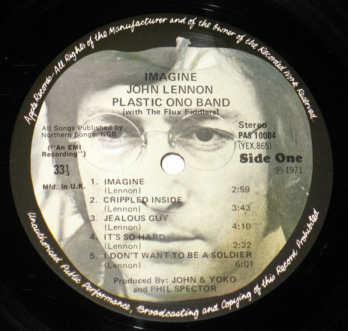 Vinyl record label of John Lennon's 'Imagine' album, featuring a black and white close-up of Lennon's face with tracklist and production credits printed over it.
